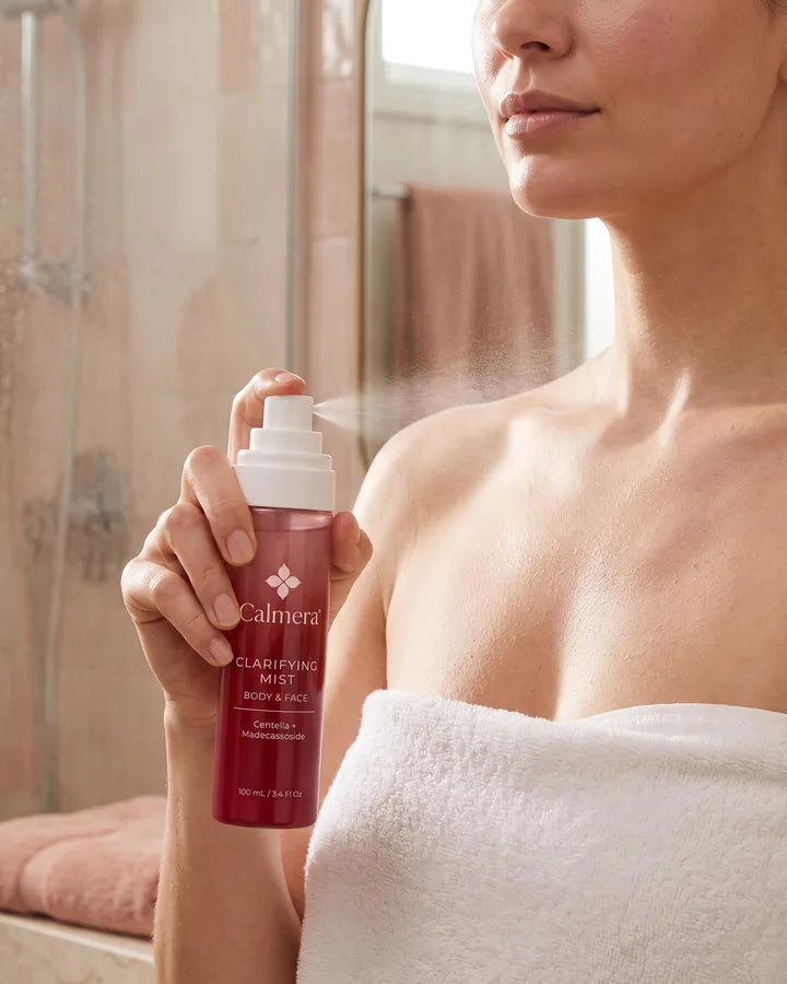 Woman in a towel spraying Calmera Clarifying Mist on her chest